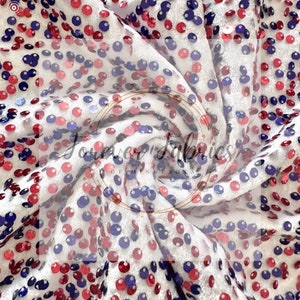 May include: White fabric with red, blue, and silver sequins in a circular pattern. The fabric is folded and twisted, creating a swirling effect. The text "Forever Fabrics of Minnesota" is visible in the center of the image.