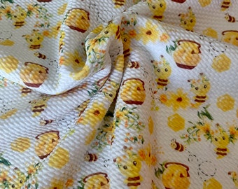 May include: White fabric with a yellow and brown honeycomb pattern. The pattern features bees, honey pots, and flowers.