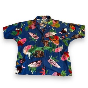 May include: A short-sleeved button-down shirt in a vibrant blue hue, adorned with a colorful pattern of various sea creatures and tropical foliage. The design includes pink, red, and brown fish, along with green leaves, creating a lively and summery aesthetic.