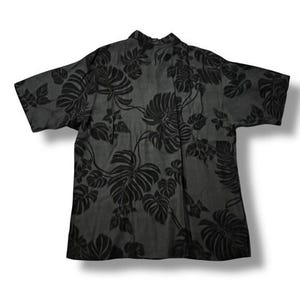 Puede incluir: Una camisa gris oscuro con un estampado de hojas tropicales negras. La camisa de manga corta presenta un cuello cl&aacute;sico y un corte relajado, adecuada para ropa informal. La camisa est&aacute; hecha de una tela ligera.