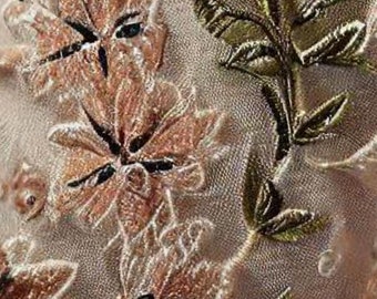 Può includere: Primo piano di un delicato tessuto rosa chiaro con ricami intricati. Il design presenta un motivo floreale con accenti marroni e verdi.