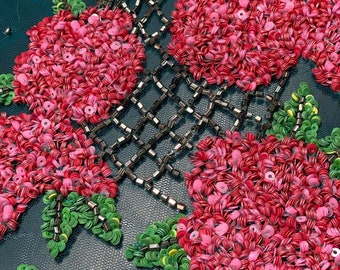 Può includere: Primo piano di un tessuto turchese con paillettes rosse, rosa e verdi disposte a forma di fiore.