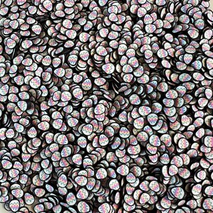 May include: A close-up shot of a pile of polymer clay slices. Each slice is egg-shaped with a white base and a colorful zigzag pattern in pastel shades. The edges are black, creating a contrast.