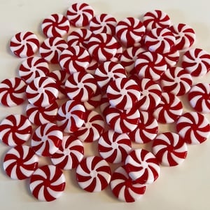 May include: A collection of red and white peppermint candies. Each candy has a spiral design with alternating red and white stripes. The candies are round and appear to be made of hard candy or plastic.