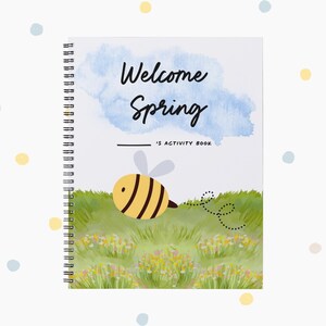 May include: A spring-themed activity book with a spiral binding. The cover displays "Welcome Spring" above a cartoon bee on a grassy field, set against a blue watercolour cloud. The design includes yellow and blue dots. The book is designed for activities.
