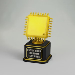May include: A gold-colored trophy featuring a square computer processor chip design with metallic pins on all sides, mounted on a black hexagonal base. The base includes a gold-bordered plaque with the text ENTER YOUR CUSTOM TEXT HERE.