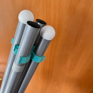 May include: Four silver poles with teal plastic clips and white plastic caps on the ends. The poles are bundled together.