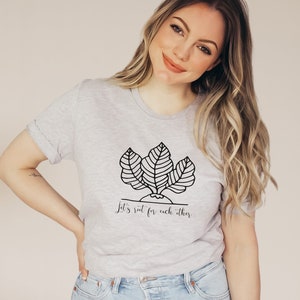 May include: A gray t-shirt with a black and white illustration of a plant with the text "Let's root for each other".
