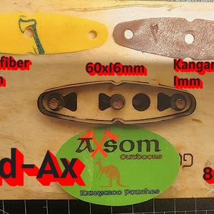 May include: An assortment of slingshot components, including yellow microfiber (1.3mm), brown kangaroo leather (1mm), and a metal frame. The image also shows the text "Broad-Ax" and "A som Outdoors".