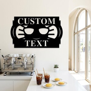 Könnte beinhalten: Ein schwarzes Metall-Wandschild mit einem ausgeschnittenen Design eines lächelnden Gesichts mit Sonnenbrille. Das Wort CUSTOM befindet sich über der Sonnenbrille und das Wort TEXT darunter, beide in einer fetten, serifenlosen Schriftart.