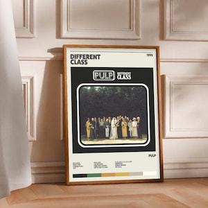 May include: A framed poster featuring the album cover for "Different Class" by Pulp. The poster has a black background with a photo of a group of people. The band's name is in a white retro font. The poster is displayed on a wooden floor.