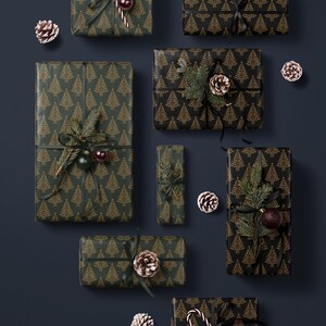 K&ouml;nnte beinhalten: Eine Sammlung von acht Weihnachtsgeschenken, die in schwarzes und goldenes Geschenkpapier mit einem Muster aus stilisierten Weihnachtsb&auml;umen verpackt sind. Die Geschenke sind mit Tannenzweigen, Zuckerstangen, Tannenzapfen und Kugeln verziert.