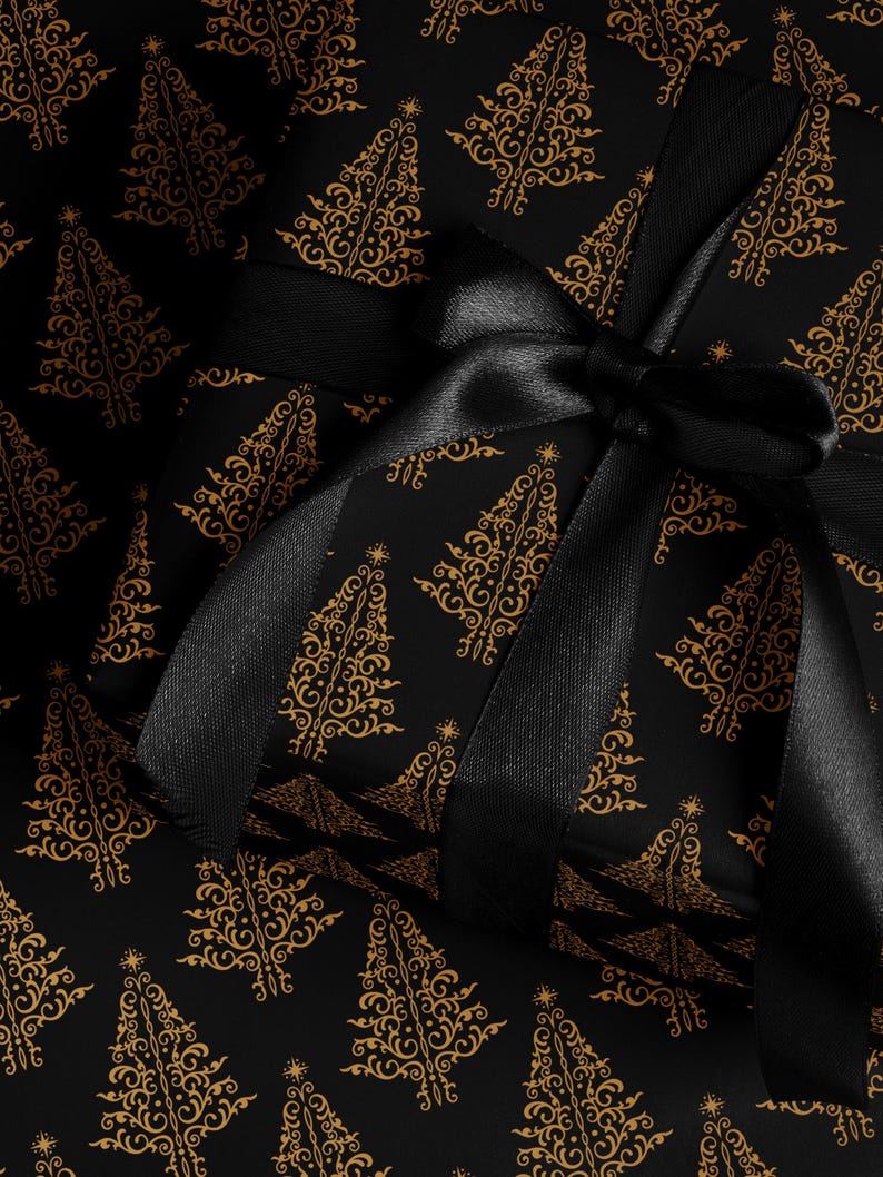 K&ouml;nnte beinhalten: Schwarzes Geschenkpapier mit einem goldenen Muster aus stilisierten Weihnachtsb&auml;umen. Ein schwarzes Satinband ist um das Geschenk gebunden.