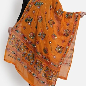 Peut inclure: Un dupatta en mousseline jaune moutarde avec des broderies colorées et des miroirs. Le dupatta a un motif floral et paisley.