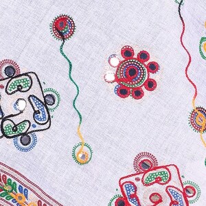May include: White fabric with colorful embroidery and small round mirrors. The embroidery features geometric shapes and floral designs.