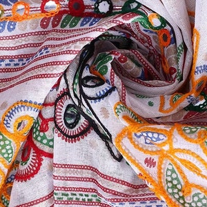 May include: White cotton fabric with colorful embroidery and mirror embellishments. The fabric has a striped pattern and features floral designs in shades of red, green, yellow, and blue.