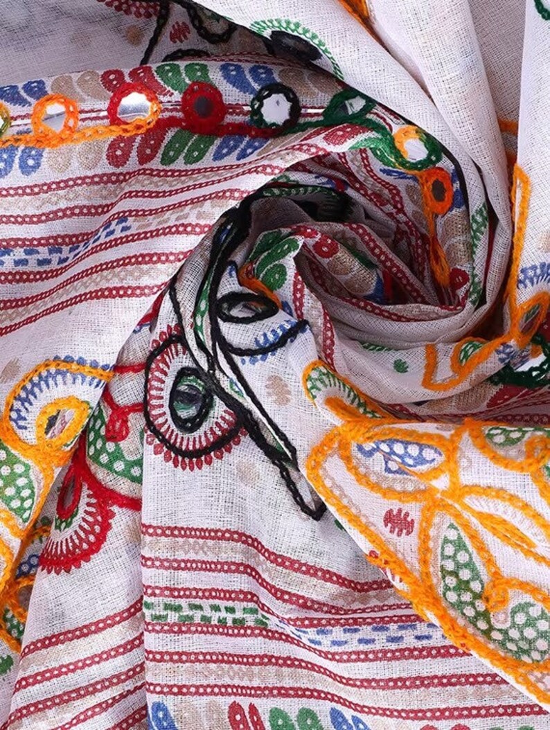 May include: White cotton fabric with colorful embroidery and mirror embellishments. The fabric has a striped pattern and features floral designs in shades of red, green, yellow, and blue.