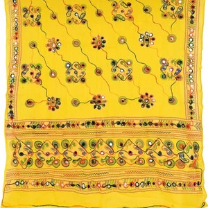 K&ouml;nnte beinhalten: Ein gelber Baumwollschal mit aufwendigen Stickereien und Spiegelarbeiten. Der Schal hat ein geometrisches Muster mit kleinen Kreisen und Quadraten. Der Rand ist mit einer Reihe von Spiegeln und einem floralen Design verziert.