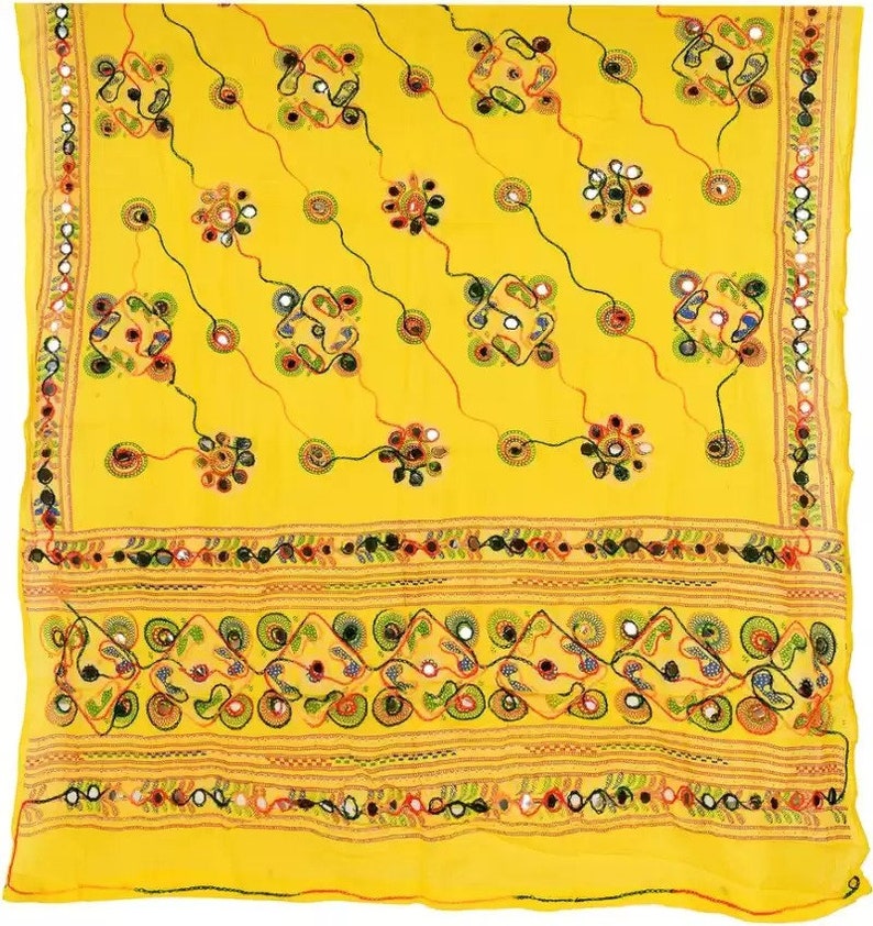 K&ouml;nnte beinhalten: Ein gelber Baumwollschal mit aufwendigen Stickereien und Spiegelarbeiten. Der Schal hat ein geometrisches Muster mit kleinen Kreisen und Quadraten. Der Rand ist mit einer Reihe von Spiegeln und einem floralen Design verziert.