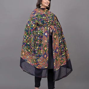 Könnte beinhalten: Ein schwarzer Dupatta mit aufwendigen, mehrfarbigen Blumenstickereien und kleinen runden Spiegeln. Der Stoff liegt über einem einfarbigen schwarzen Outfit, bestehend aus einer langen Tunika und einer schmalen Hose, mit lebhaften Mustern.