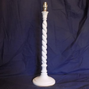 May include: A white table lamp with a twisted column design. The lamp has a round base and a bulb socket at the top. The lamp is approximately 61 cm tall.