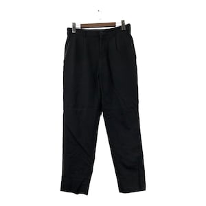 May include: Black trousers hanging on a wooden hanger. The pants have a button closure, belt loops, and pockets. The fabric appears to be a medium-weight material. The trousers are a solid black color.
