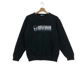 May include: Black sweatshirt with a white graphic print of a stylized face and the word "BESCHWA".