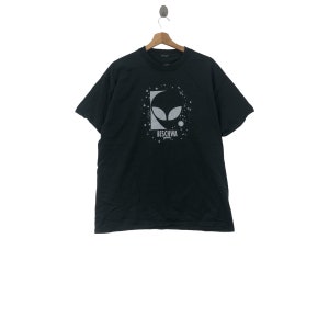 May include: Black t-shirt with a silver alien graphic and the text "Beschwa" printed on the front.