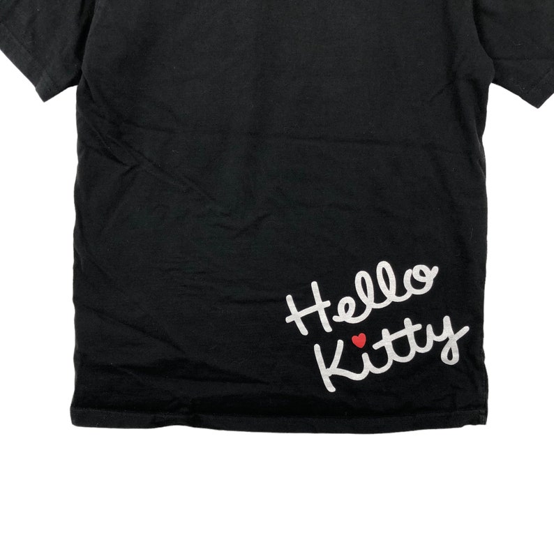 K&ouml;nnte beinhalten: Schwarzes T-Shirt mit einem wei&szlig;en "Hello Kitty"-Motiv mit einem roten Herzen.