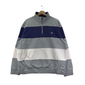 May include: A gray, white, and blue striped quarter-zip sweatshirt with a small logo on the chest.