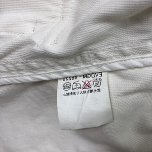 May include: White care label with black text that reads "EVDGM - 88-230". The label also has a graphic of a washing machine with a circle around it and a line through it. The text "30" is inside the circle. There is also a graphic of an iron with a circle around it and a line through it. The text "中" is inside the circle. There is also a graphic of a triangle with a circle around it and a line through it. The text "ドライ" is inside the circle. The text "禁止漂白" is also on the label.