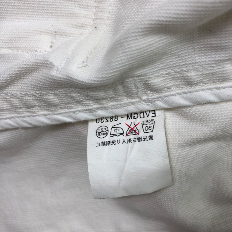 May include: White care label with black text that reads "EVDGM - 88-230". The label also has a graphic of a washing machine with a circle around it and a line through it. The text "30" is inside the circle. There is also a graphic of an iron with a circle around it and a line through it. The text "中" is inside the circle. There is also a graphic of a triangle with a circle around it and a line through it. The text "ドライ" is inside the circle. The text "禁止漂白" is also on the label.