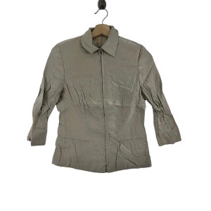 May include: A light brown zip-up jacket with a collared neckline and long sleeves.