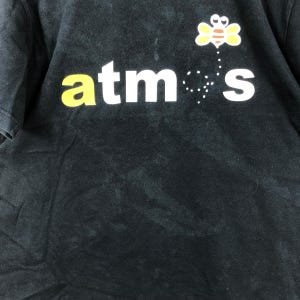 May include: Black t-shirt with the word "atmos" in yellow and white, and a cartoon bee graphic. The bee is yellow, white, and brown. The shirt is slightly faded.