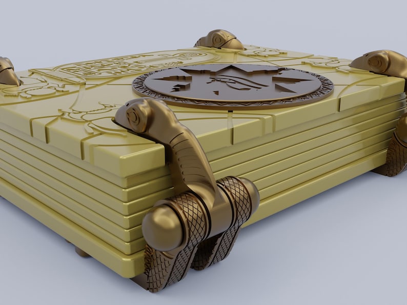 May include: A gold-colored book with intricate details and a circular design on the cover. The book has a series of clasps that are secured with a decorative metal hinge.