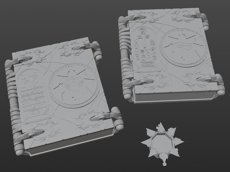 May include: Three gray 3D printed models of a book with intricate designs and a star-shaped object. The book has a detailed design with a circular pattern and text on the cover.