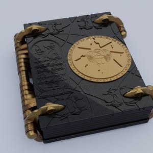 May include: A black book with gold accents and a circular design featuring an Egyptian scarab beetle. The book has a textured cover and multiple clasps.