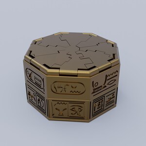 May include: A gold-colored octagonal box with intricate carvings and a hinged lid. The box is decorated with hieroglyphic-like symbols.