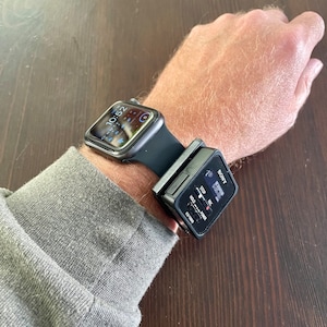 May include: A black Apple Watch with a digital clock face showing 10:52 is worn on a person's wrist. A black Sony ICD-PX333 digital voice recorder is attached to the watch band.