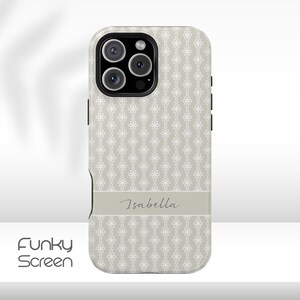 Puede incluir: Funda de teléfono con un estampado floral blanco sobre un fondo gris claro. Una banda gris claro en la funda presenta el nombre "Isabella" en una fuente de escritura. La funda tiene un módulo de cámara negro.