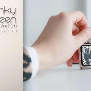 Puede incluir: Un smartwatch de color oro rosa con una esfera de reloj con un patr&oacute;n en blanco y negro que presenta una mano con una estrella y la hora 22:15. El reloj est&aacute; sobre una superficie blanca.