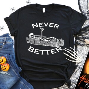 May include: Black t-shirt featuring a white graphic of a skeleton lying in a coffin with the text "Never Better". The t-shirt is on a white background with a black spiderweb, a skull, and a Halloween party invitation.