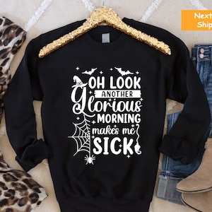 May include: Black sweatshirt with a white graphic that says "Oh look another glorious morning makes me sick" with a witch hat, spider web, and bats.