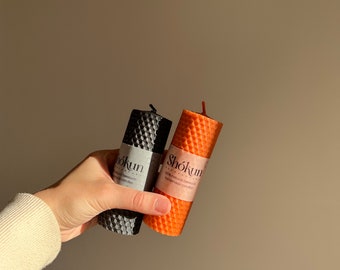 May include: Two honeycomb candles, one black and one orange, with the text "Shōkun 100% natural beeswax handmade candles" on the orange candle.