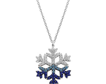 Op de afbeelding: Een zilverkleurige ketting met een sneeuwvlokvormige hanger versierd met een verloop van fonkelende steentjes. Het bovenste gedeelte is bezet met helderwitte stenen, die in het midden overgaan in lichtblauw en onderaan in donkerblauwe stenen.