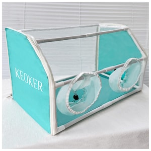 May include: A portable teal and white glove box with a clear mesh top and front panel. The side features the white text KEOKER. It includes two circular arm ports with elasticized cuffs and a white frame structure for a rectangular enclosure.