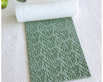 May include: A white silicone rolling pin and a green silicone mat with a leaf pattern. Both are used for decorating cakes and pastries.