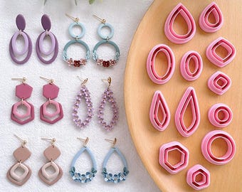 May include: A collection of handmade earrings in various shapes and colors, including purple, pink, and blue. The earrings feature geometric designs, floral accents, and layered elements. Also shown are pink polymer clay cutters in various shapes, including teardrops, ovals, and hexagons.