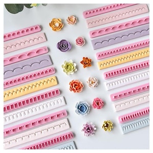 Könnte beinhalten: Eine Sammlung von Silikon-Bordürenformen in verschiedenen Pastellfarben wie Rosa, Lila, Gelb und Blau mit gewellten, gezackten und dekorativen Kantenmustern, ergänzt durch mehrere kleine, mehrfarbige künstliche Blumenverzierungen.
