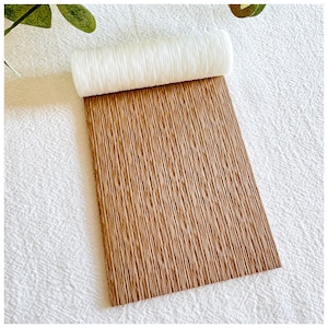 Puede incluir: Un rollo de papel texturizado marrón con un núcleo de papel blanco. El papel tiene un patrón de veta de madera.